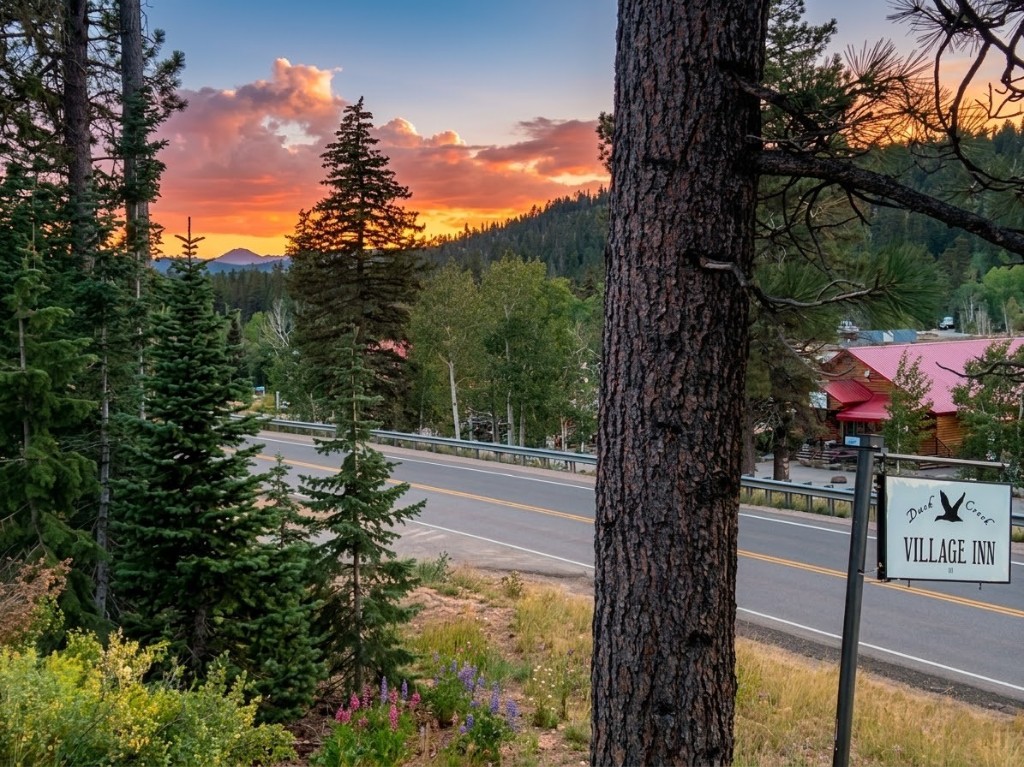 Duck Creek Village Inn sign with mountain and village sunset view