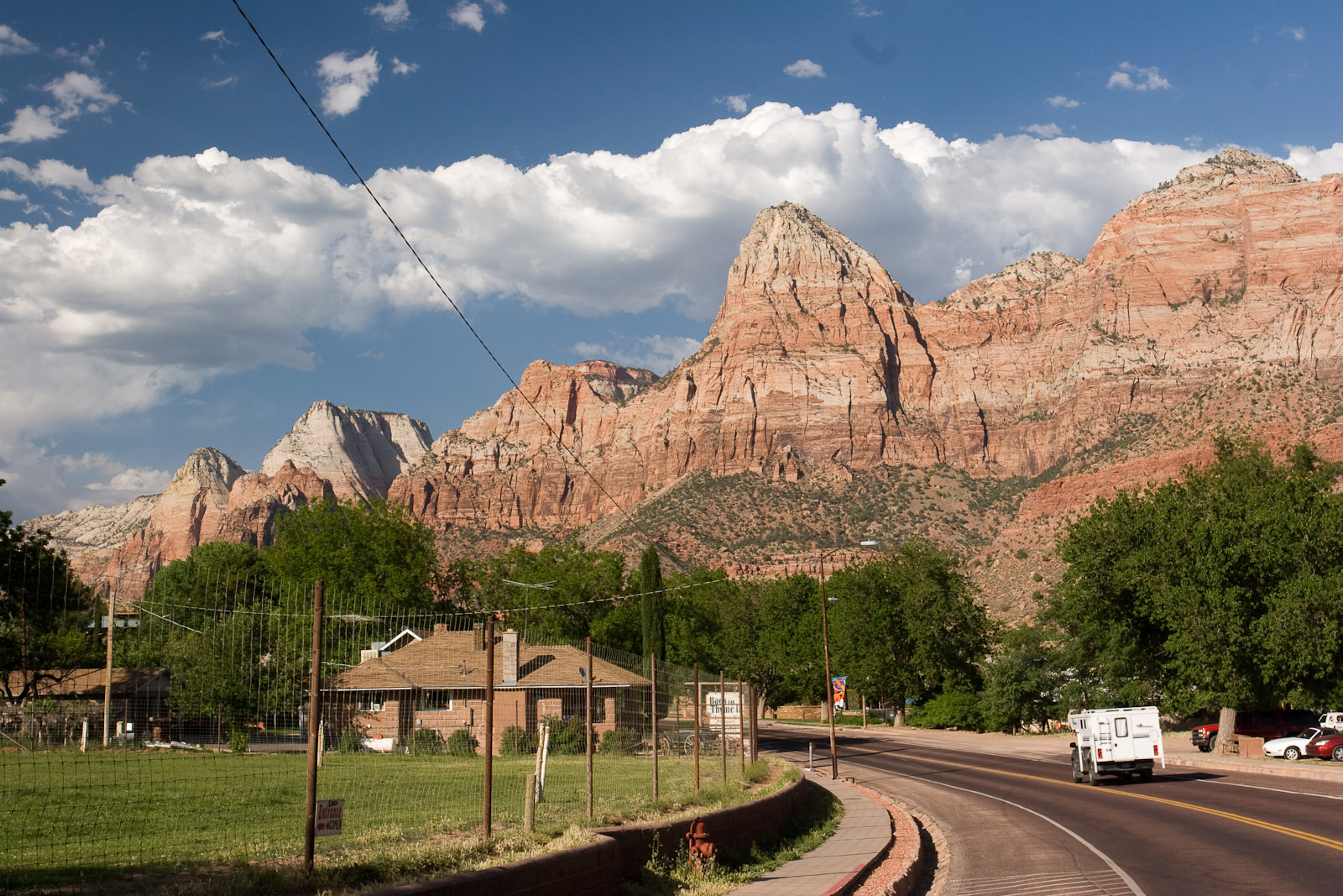 Road curving into Springdale, Utah, beneath towering red canyon cliffs