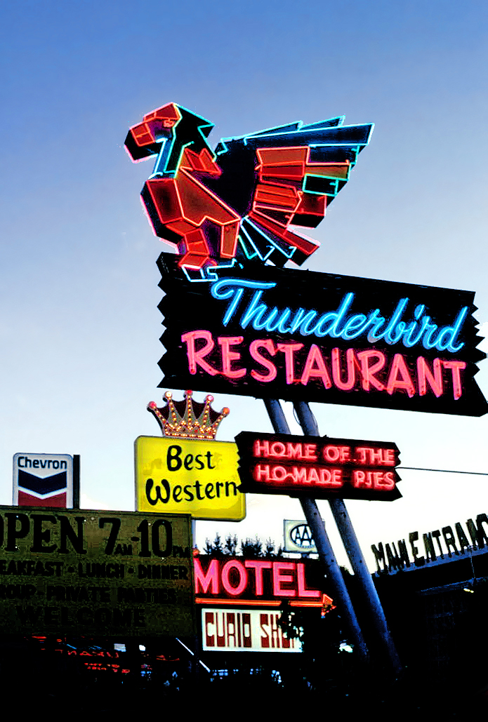 Neon Thunderbird Restaurant sign at dusk with the "Home of the Ho-Made Pies" panel lit below