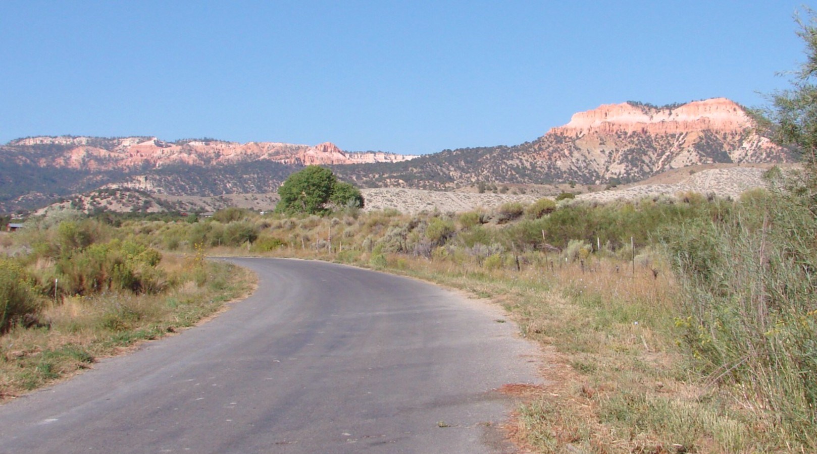 Quiet road outside Tropic, Utah, with the pink cliffs of Bryce Canyon glowing behind