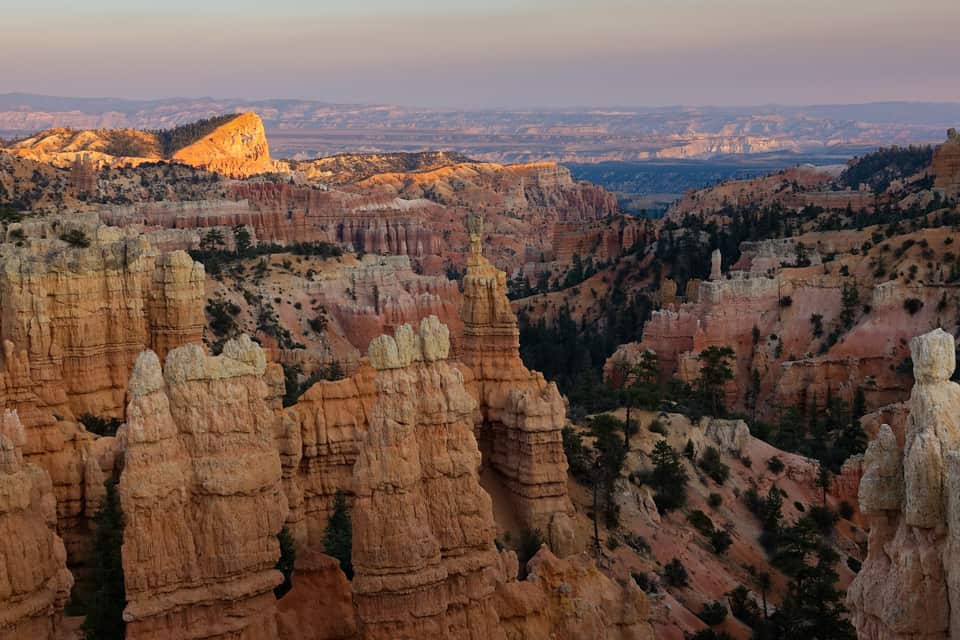 Fairyland Point at first light, hoodoos glowing pink and orange with Boat Mesa behind (NPS photo by Peter Densmore)