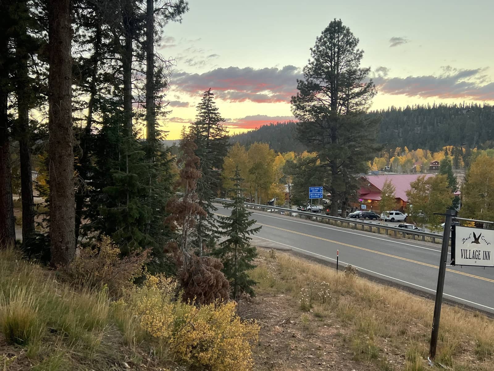 Sunset over Highway 14 in front of Duck Creek Village Inn with aspens turning gold across the road