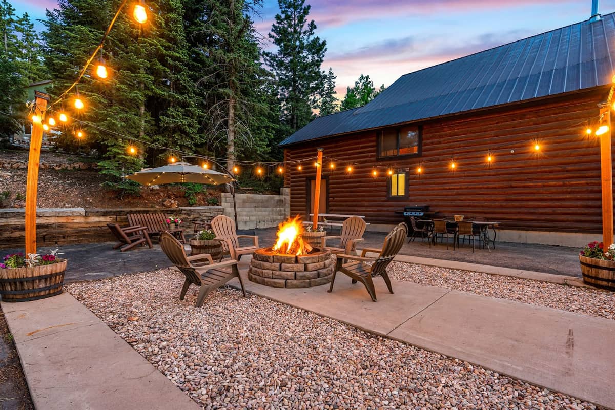 Firepit seating and string lights beside Duck Creek Village Inn at twilight