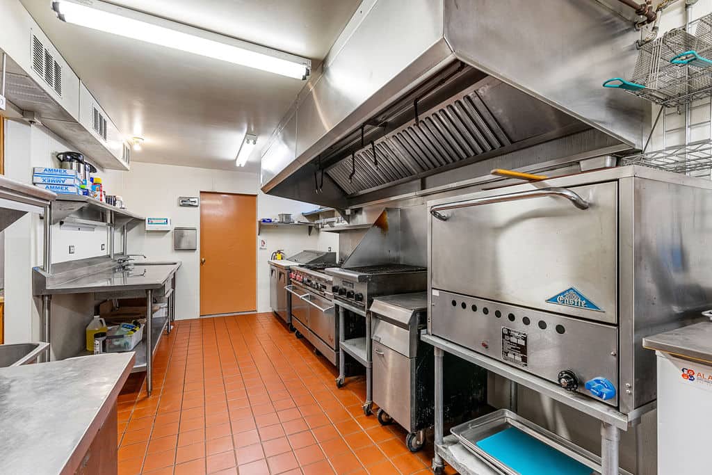 Commercial kitchen with stainless steel range, grill, and convection oven for group meals during a hotel buyout.