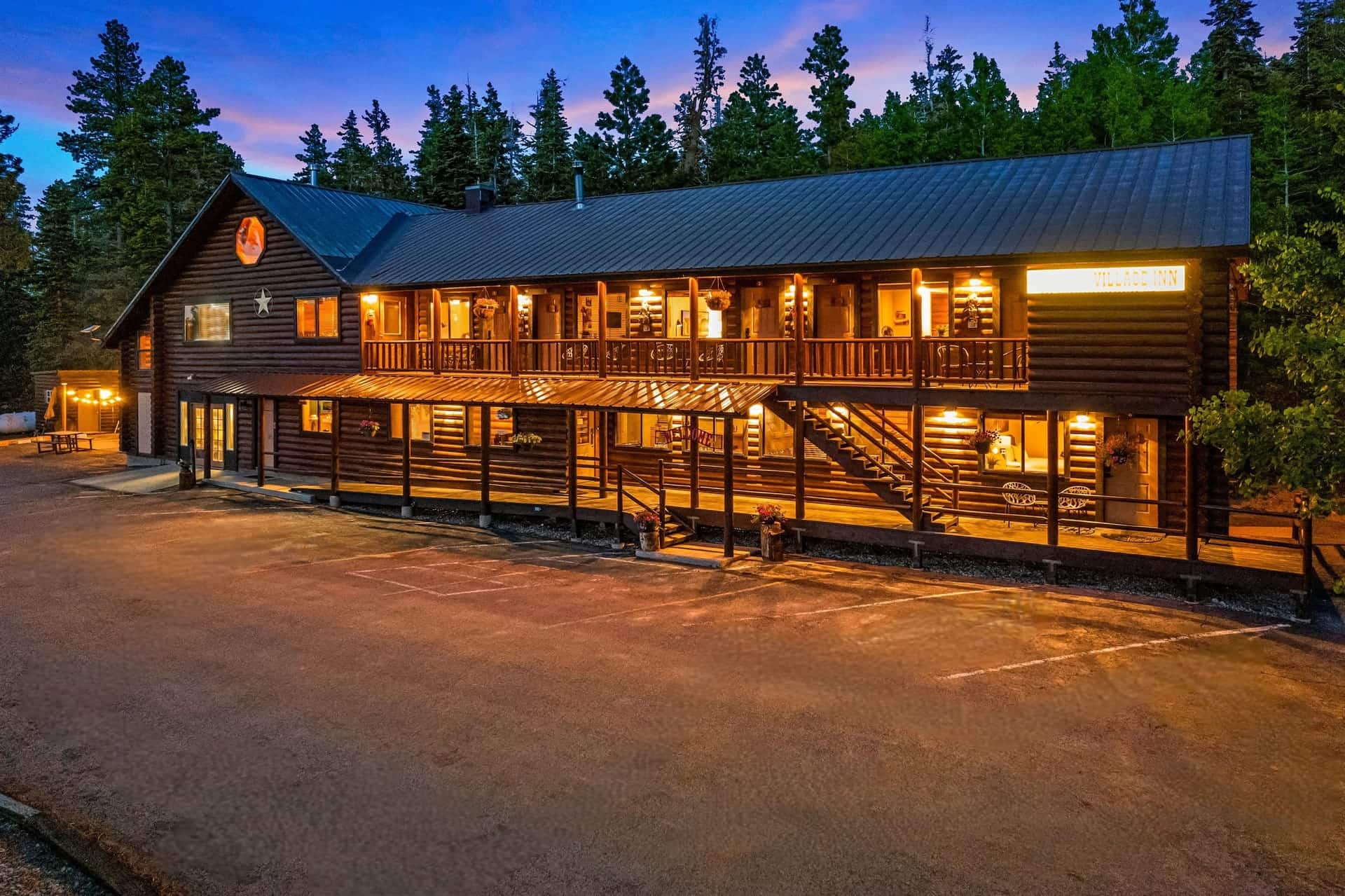 Le lodge du Duck Creek Village Inn au crépuscule, avec la terrasse des chambres éclairée à l’étage