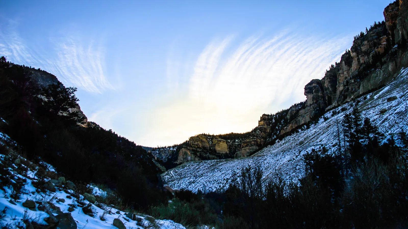 Schnee an den Hängen unter den Sandsteinklippen des Cedar Canyon in Utah, im Winter unter hohen Schleierwolken
