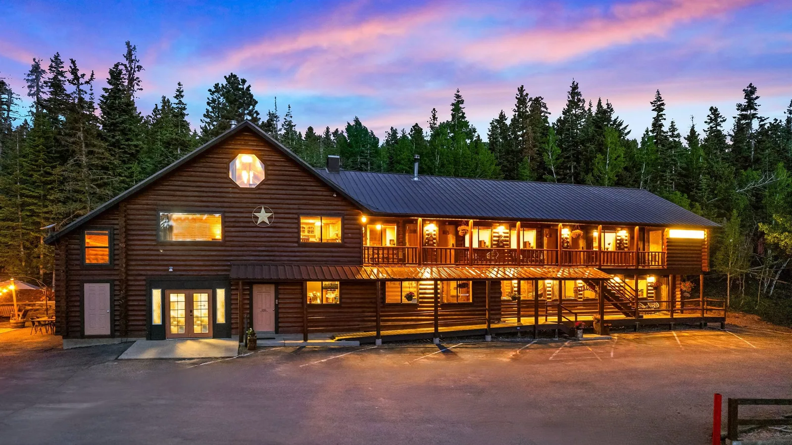 Duck Creek Village Inn lit at twilight above its marked parking lot with spruce and aspen behind the log building