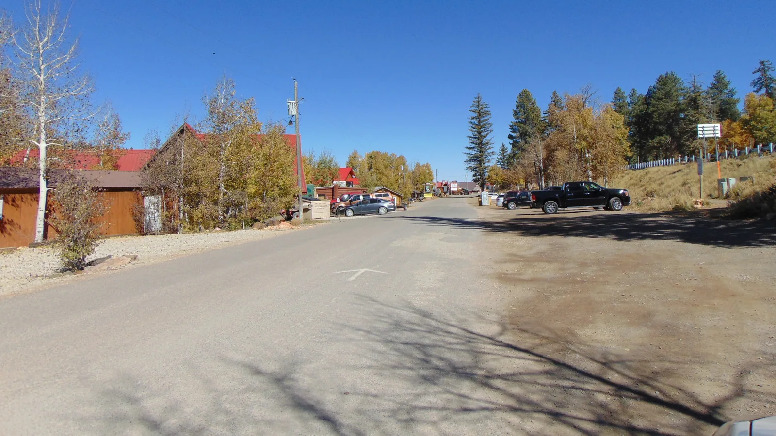 Movie Ranch Road traversant Duck Creek Village, Utah, vers l'est, devant les commerces du village sous les trembles d'automne
