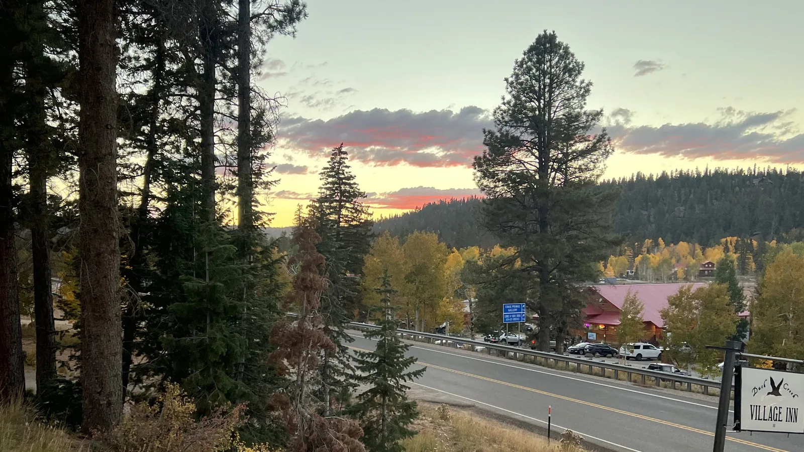 La Highway 14 au coucher du soleil à Duck Creek Village, avec l'enseigne du Duck Creek Village Inn et des trembles jaunes le long de la route