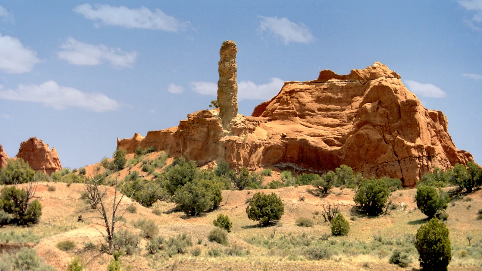 Een hoge zandstenen zandpijp die oprijst naast een oranje rotsrichel boven jeneverbesstruiken en salie in Kodachrome Basin State Park, Utah