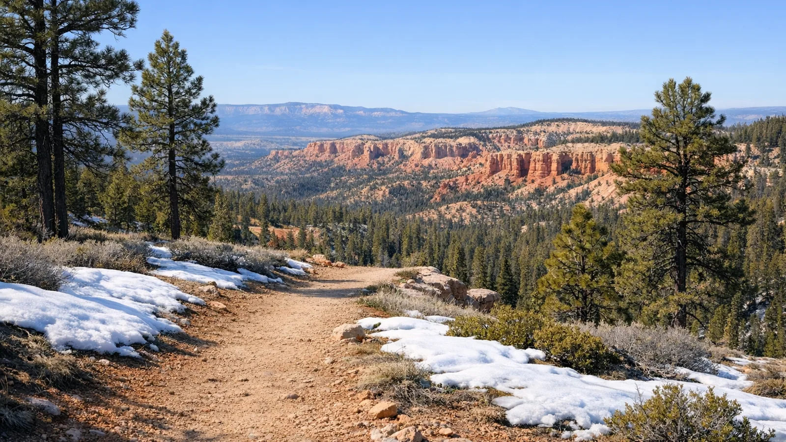 Spring plateau scene with pines, light snow, and broad red rock tones near Bryce country