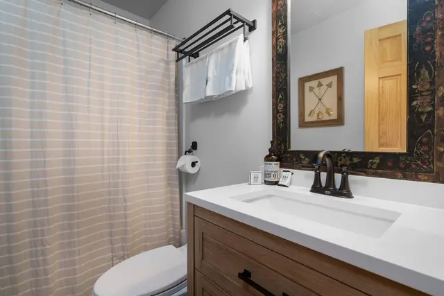 Updated bathroom with a white vanity, black fixtures and a tub with shower curtain
