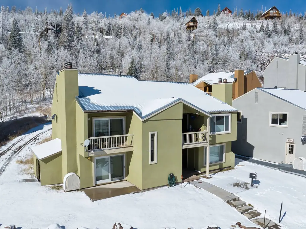 Aerial view of the condo building in fresh snow with aspen and fir trees behind it