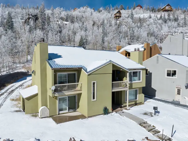 Aerial view of the condo building in fresh snow with aspen and fir trees behind it