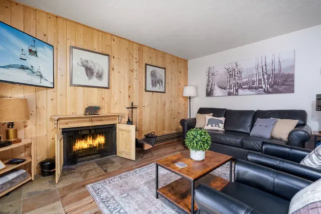 Wood-burning fireplace with a fire lit, set into a pine-paneled wall