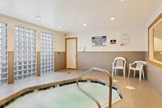 Indoor community hot tub with glass-block windows and chairs alongside