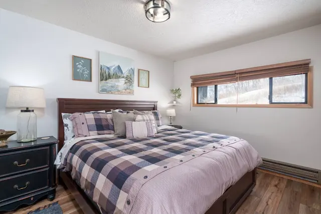 Bedroom with a king bed under a plaid quilt and a window above the headboard
