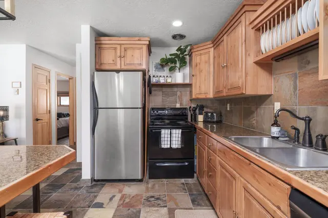 Kitchen with a stainless fridge, black range, double sink and stocked shelves