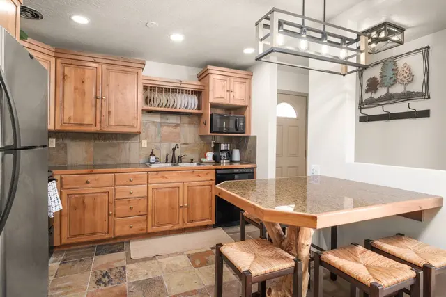 Kitchen with wood cabinets, slate floors and a dining table with rush-seat stools