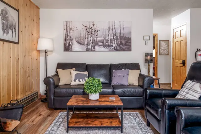 Living room with a leather sofa and loveseat, a wood coffee table and aspen artwork