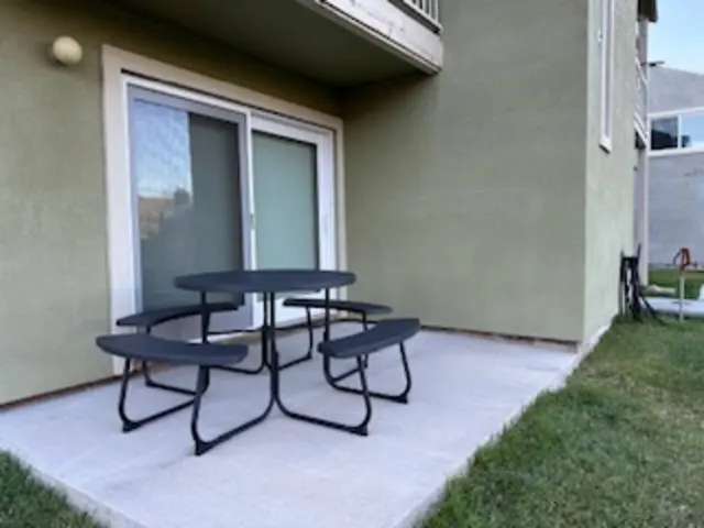 Concrete patio outside the sliding door with a black picnic table