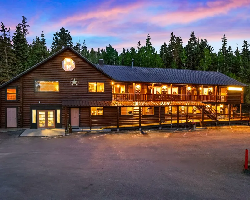 Warmly lit Duck Creek Village Inn beneath pine trees at twilight